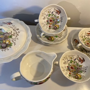 May include: A set of vintage white ceramic bowls with a floral and fruit design. The bowls have a scalloped edge and are perfect for serving soup or salad.