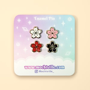 Pode incluir: Conjunto de quatro pinos de esmalte com flores de cerejeira em vermelho, rosa, preto e branco. Os pinos são exibidos em um cartão com fundo pastel e o texto "Enamel Pin" e "www.mochiville.com".