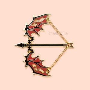 May include: Gold-tone bow and arrow pin with red wings. The bow is connected to the arrow by a gold chain.