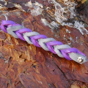 Op de afbeelding: Een paarse en grijze gevlochten leren sleutelhanger met een zilveren sleutelring.