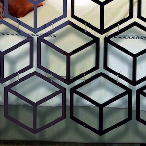 May include: Black geometric room divider made of multiple connected hexagonal shapes with a 3D cube design. The divider is hanging on a wall and is made of a thin, lightweight material.