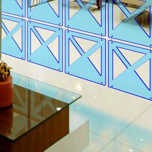 May include: A blue geometric room divider made of acrylic panels with a criss-cross pattern. The divider is hanging from the ceiling and is in front of a glass coffee table.