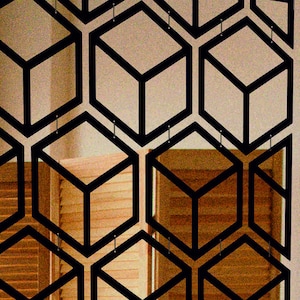 May include: A black metal room divider with a geometric pattern of overlapping cubes. The divider is made of thin metal and creates a modern and stylish look.