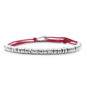 Peut inclure: Un bracelet argenté composé d'une série de petites perles métalliques rondes enfilées. Le bracelet est doté d'un cordon rouge et d'un fermoir argenté. Le bracelet est présenté sur fond blanc.