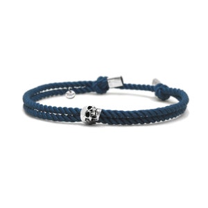 May include: A dark blue rope bracelet with a silver skull charm.