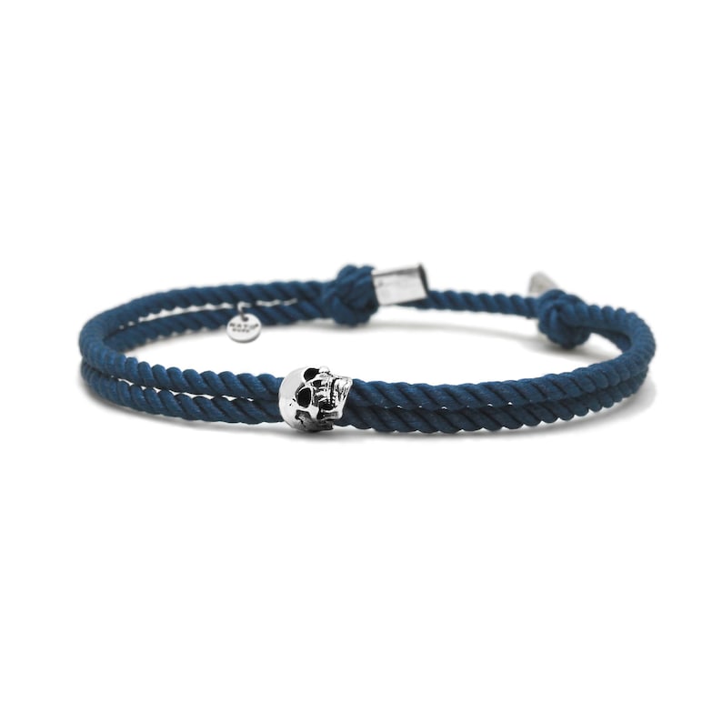 May include: A dark blue rope bracelet with a silver skull charm.