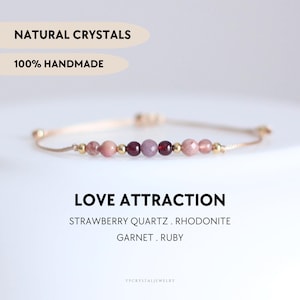 Könnte beinhalten: Ein zartes Armband mit facettierten Erdbeerquarz-, Rhodonit-, Granat- und Rubinperlen, unterbrochen von kleinen goldfarbenen Metallkugeln. Der Text lautet: NATURAL CRYSTALS, 100% HANDMADE, LOVE ATTRACTION, STRAWBERRY QUARTZ, RHODONITE, GARNET, RUBY, YPCRYSTALJEWELRY.
