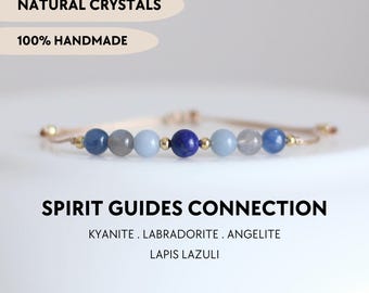 May include: A beaded bracelet featuring natural kyanite, labradorite, angelite, and lapis lazuli stones interspersed with small gold-toned metal beads on a thin cord. Text reads: NATURAL CRYSTALS, 100% HANDMADE, SPIRIT GUIDES CONNECTION, KYANITE, LABRADORITE, ANGELITE, LAPIS LAZULI, YPCRYSTALJEWELRY.