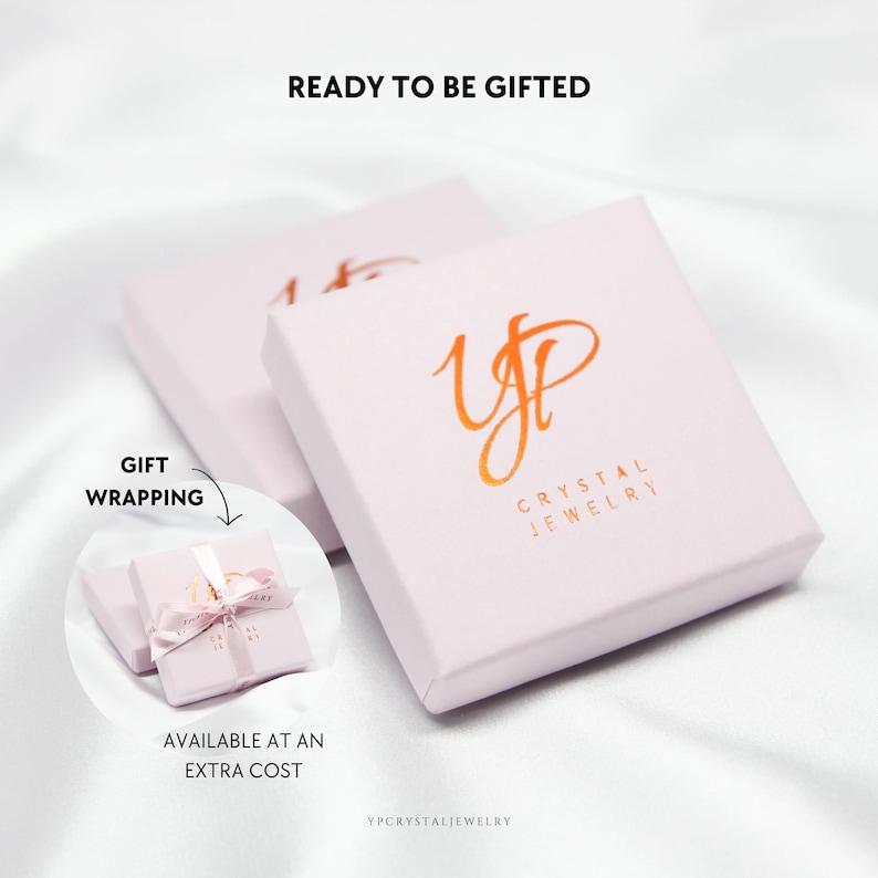 May include: Two square light pink jewelry boxes featuring the orange logo YP CRYSTAL JEWELRY. The text READY TO BE GIFTED appears above. A circular inset shows a box tied with a light pink ribbon, labeled GIFT WRAPPING AVAILABLE AT AN EXTRA COST.