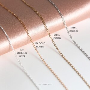 May include: Four silver chains on a pink background. The chains are labelled from left to right: 925 Sterling Silver, 18K Gold Plated, Steel (Gold), Steel (Silver).
