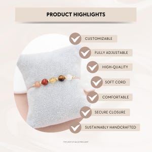 May include: A gold bracelet featuring a string of colourful gemstones, including pink, red, yellow, brown, and white beads. The bracelet is presented on a grey cushion. The image includes the text "PRODUCT HIGHLIGHTS" and "YPCRYSTALJEWELRY".