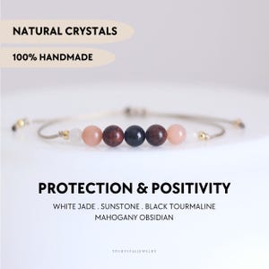 Puede incluir: Una pulsera de cuentas en un cordón claro con jade blanco, piedra de sol, obsidiana caoba y turmalina negra. El texto en la imagen dice: NATURAL CRYSTALS, 100% HANDMADE, PROTECTION & POSITIVITY, WHITE JADE, SUNSTONE, BLACK TOURMALINE, MAHOGANY OBSIDIAN.