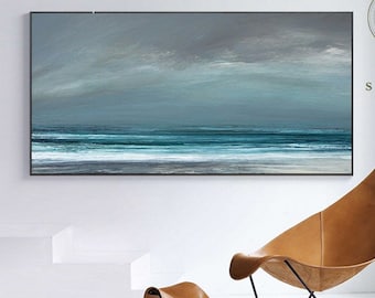 May include: A painting depicting a seascape with a blue and green ocean and a white sandy beach. The painting is framed in black and hangs on a white wall. A brown leather chair and footstool are in the foreground.
