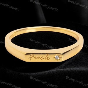 May include: A gold band ring with a small diamond and the word "Forever" engraved on the top.