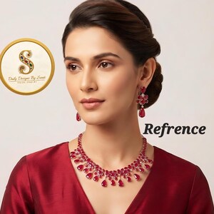 May include: A jewelry set consisting of a necklace and matching drop earrings, each featuring multiple teardrop-shaped red stones set in a metallic frame. The necklace has a tiered arrangement of these red stones, and the earrings mirror the design.