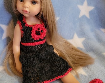 May include: A doll with long blonde hair wearing a black and red crocheted dress with a red flower on the bodice. The doll is wearing red crocheted shoes and a red headband with a red flower.