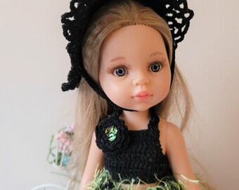 May include: A doll with blonde hair wearing a black crocheted hat and dress with a green fluffy skirt.