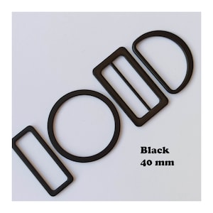 May include: Four black metal belt buckle hardware pieces in different shapes: a circle, a rectangle, a rectangle with a centre bar, and a half-circle. The hardware is 40 mm in size. Black 40 mm.