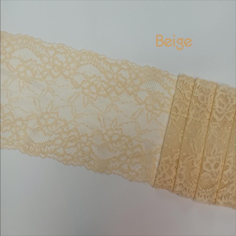 May include: Beige lace trim with a floral pattern. The lace is delicate and has a soft, flowing texture.