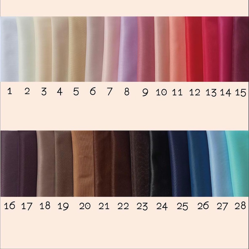 May include: A swatch card with 28 fabric samples. The samples are arranged in two rows of 14. The top row includes white, cream, beige, light pink, lavender, light blue, and red fabric samples. The bottom row includes dark purple, brown, tan, dark brown, black, navy blue, light blue, and turquoise fabric samples.