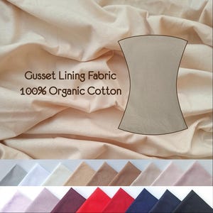 Puede incluir: Primer plano de una tela de algodón orgánico beige con el texto "Gusset Lining Fabric 100% Organic Cotton". Se muestra una muestra de la tela en el centro de la imagen. Debajo de la tela, hay 10 muestras de tela en diferentes colores: gris, blanco, beige, marrón, marrón claro, rosa, granate, rojo, azul marino y azul oscuro.