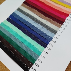 May include: A variety of colors of elastic trim with scalloped edges. The trim is numbered 1 through 27.