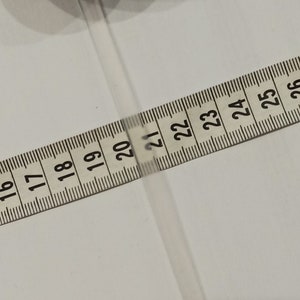 Puede incluir: Una cinta m&eacute;trica blanca con n&uacute;meros negros del 15 al 27.