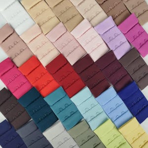 Op de afbeelding: Een set van drie keramische mokken met een gespikkelde, matte afwerking. De mokken zijn in crème, lichtgrijs en donkergrijze tinten. Elke mok heeft een eenvoudig, minimalistisch ontwerp.