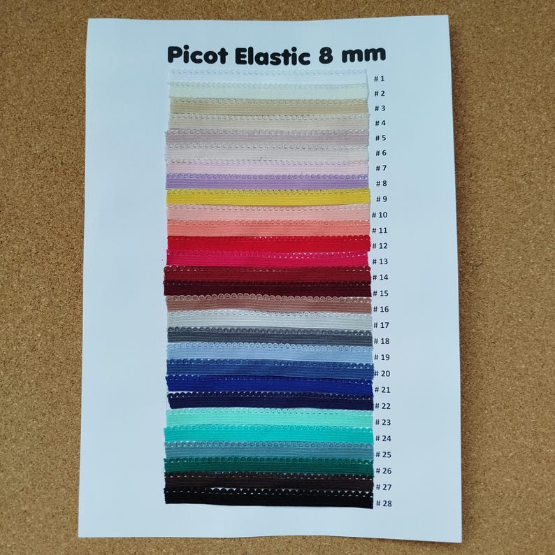 May include: A color chart of 28 different colors of 8 mm picot elastic. The elastic is arranged vertically in rows, with each color labeled with a number from 1 to 28.