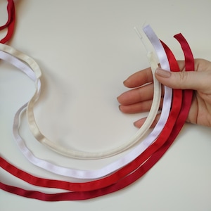 Puede incluir: Cuatro cintas diferentes, dos rojas y dos blancas, están dispuestas en semicírculo sobre una superficie blanca. Las cintas tienen aproximadamente 1,2 cm de ancho.