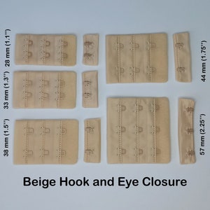 Può includere: Chiusure a gancio e occhiello per reggiseno di colore beige in diverse dimensioni. Le chiusure sono realizzate in un materiale morbido e flessibile e hanno una finitura liscia. Le dimensioni sono 38 mm, 33 mm, 28 mm, 57 mm e 44 mm.