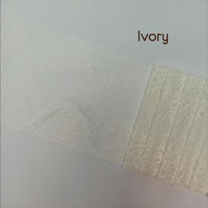 May include: Two pieces of ivory lace fabric. One piece has a delicate floral pattern, while the other has a more intricate design with vertical lines.