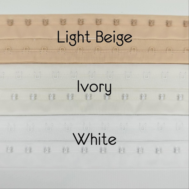 May include: Image showing three rows of hook and eye closures in light beige, ivory, and white. The text "Light Beige", "Ivory", and "White" are displayed below each respective row. These closures are used in clothing.