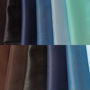 May include: A collection of fabric swatches in various shades of blue, brown, black, and green. The swatches are arranged in rows, with the top row showing lighter shades and the bottom row showing darker shades.