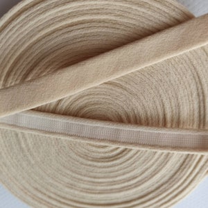 Puede incluir: Primer plano de un rollo de cinta el&aacute;stica beige con una banda el&aacute;stica blanca en la parte superior. La cinta es suave y el&aacute;stica, perfecta para a&ntilde;adir un toque de elegancia a cualquier proyecto.