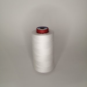 Pu&ograve; includere: Un'bobina di filo bianco con un'bobina di plastica rossa e blu.