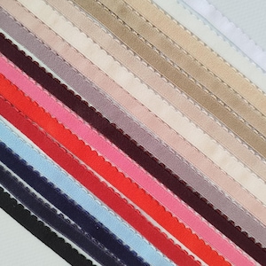 May include: A collection of 14 different colors of scalloped elastic trim. The trim is arranged in a fan shape, with the lightest colors at the top and the darkest colors at the bottom.