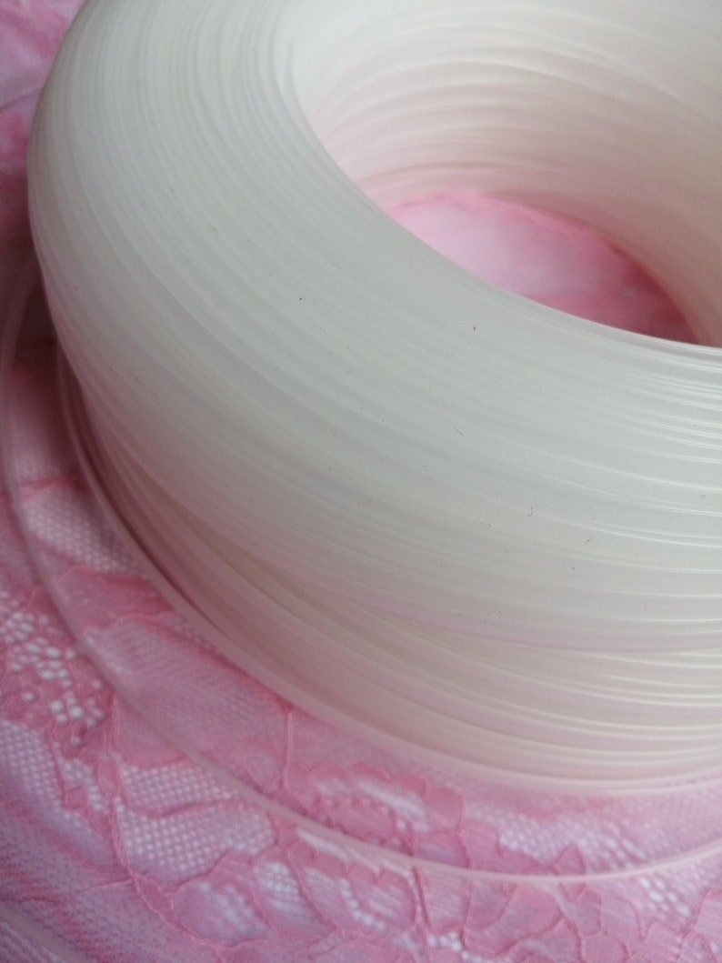Puede incluir: Primer plano de una bobina de hilo de pl&aacute;stico blanco. La bobina est&aacute; enrollada apretadamente y tiene un acabado liso y brillante.