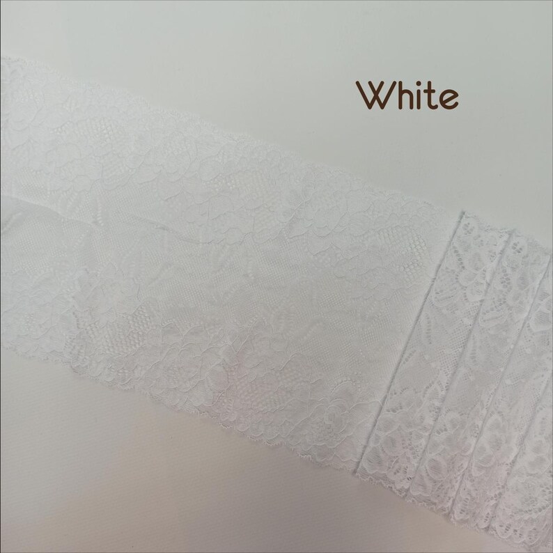 May include: White lace trim with a delicate floral pattern. The lace is soft and flexible, making it ideal for adding a touch of elegance to any project.