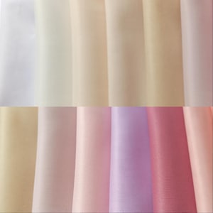 May include: A collection of ten fabric swatches in various shades of white, pink, and lavender. The swatches are arranged in a row, with the lightest shade on the left and the darkest shade on the right.