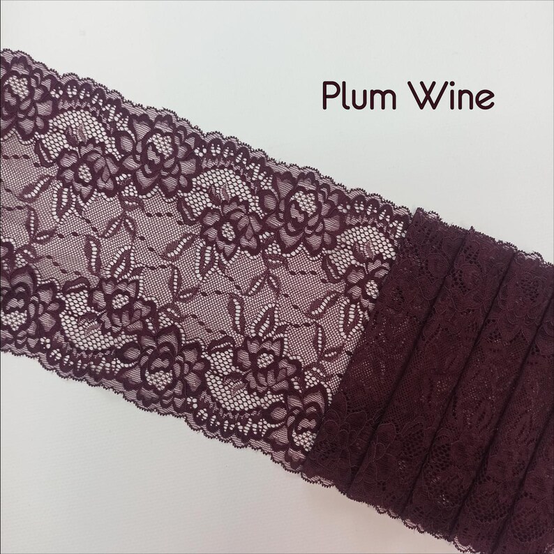 May include: Plum Wine colored lace trim with a floral pattern. The lace is folded and stacked to show the depth of the color.