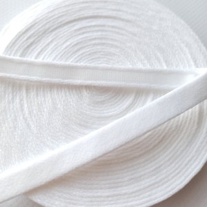 Puede incluir: Borde el&aacute;stico blanco con una textura suave y peluda. El borde est&aacute; enrollado y muestra la banda el&aacute;stica debajo.