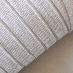 May include: White cotton twill tape with a herringbone pattern. The tape is rolled up and the edges are visible.