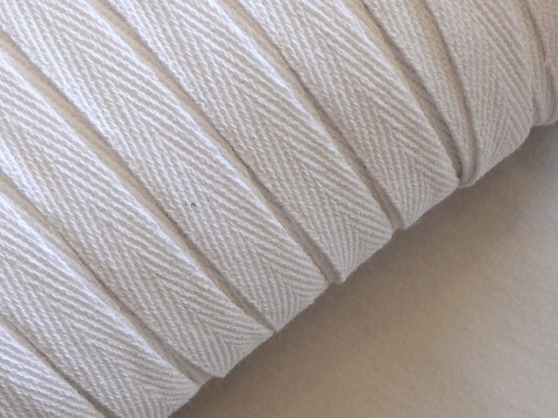 May include: White cotton twill tape with a herringbone pattern. The tape is rolled up and the edges are visible.