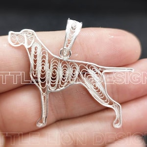 May include: A silver filigree pendant in the shape of a German Shorthaired Pointer dog. The pendant is detailed and intricate, with a delicate design.