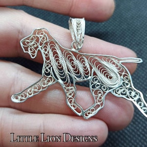Op de afbeelding: Zilveren filigraan hanger in de vorm van een hond. De hanger is gedetailleerd en ingewikkeld, met een delicaat ontwerp.