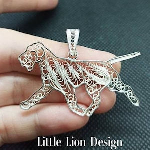 Op de afbeelding: Een zilveren filigraan hanger in de vorm van een rennende hond. De hanger is gedetailleerd en ingewikkeld, met een delicaat ontwerp.