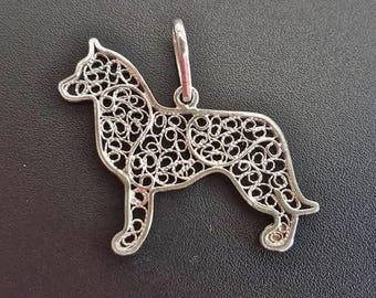 Op de afbeelding: Een zilveren filigraan hanger in de vorm van een hond. De hanger is gedetailleerd en ingewikkeld, met een delicaat ontwerp.