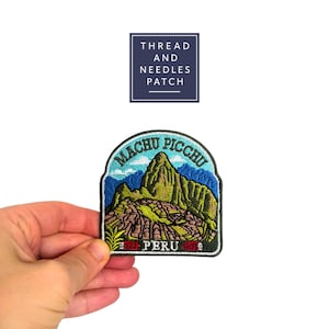 May include: Embroidered patch featuring the Machu Picchu mountain landscape in Peru. The patch has a blue border with the words "Machu Picchu" and "Peru" in white. The patch also has the text "Thread and Needles Patch".