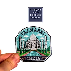 May include: Embroidered patch depicting the Taj Mahal in India. The patch has a teal background with white clouds and a detailed image of the monument. The words "TAJ MAHAL" are arched across the top, and "INDIA" is at the bottom.